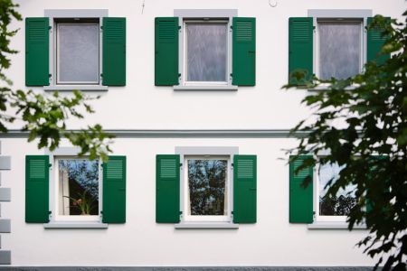Hausfassade mit sechs klassischen, grünen Klappläden der Firme Ehret 