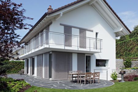 modernes Haus mit grauen, lamelleartigen Schiebeläden